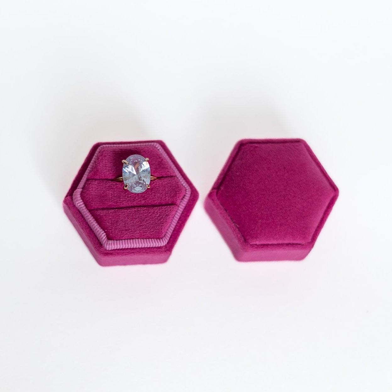 A fuchsia hexagon ring box lays open displaying the two ring slots in the base.
