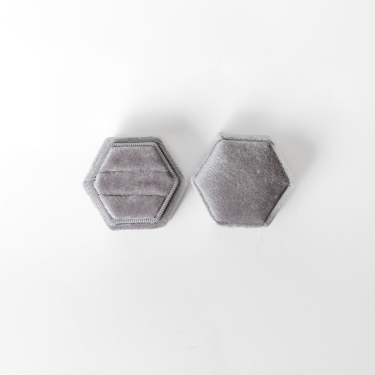 A silver hexagon ring box lays open displaying the two ring slots in the base.