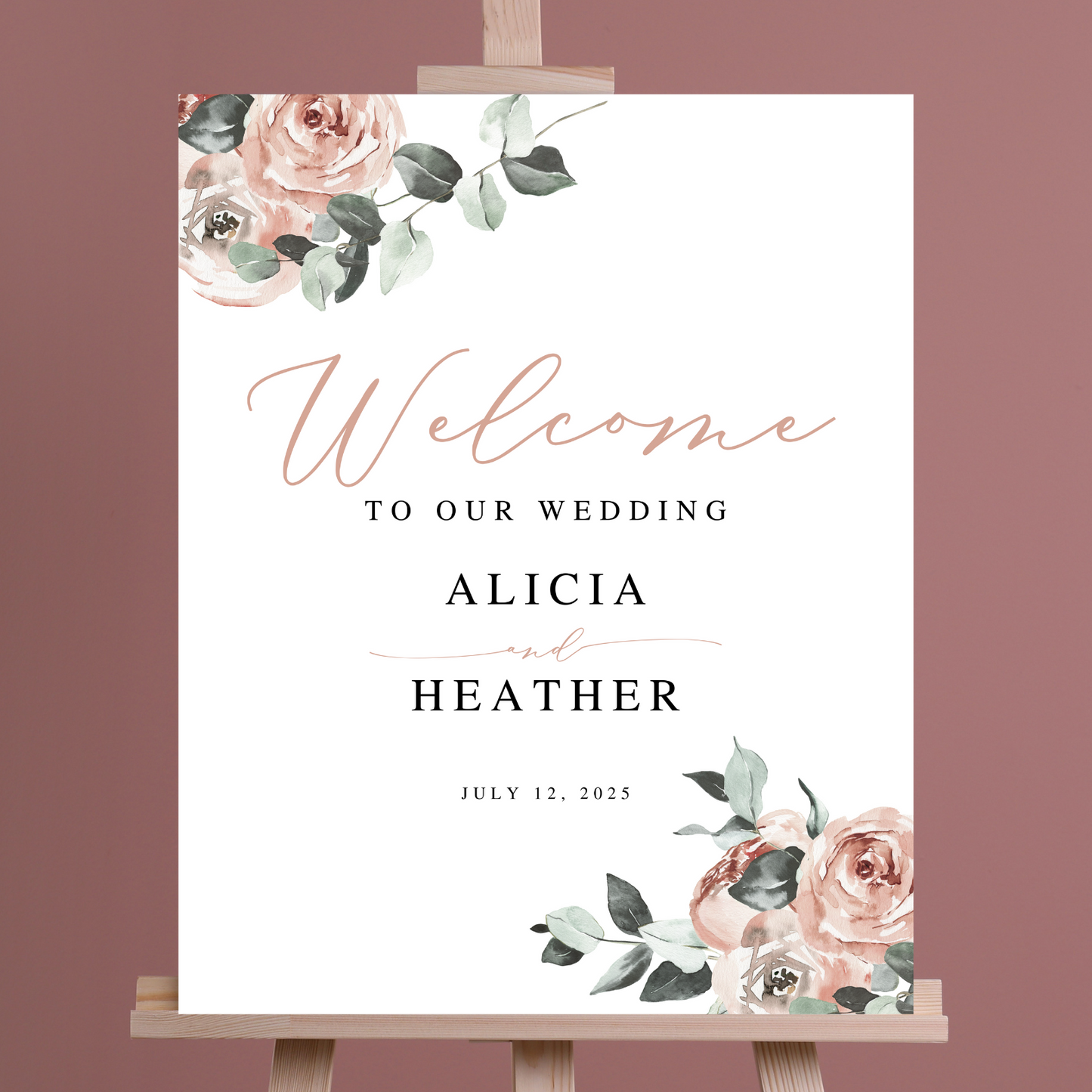 A wedding welcome sign with blush coloured florals sits on an easel against a dark pink background.