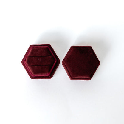 A merlot hexagon ring box lays open displaying the two ring slots in the base. 