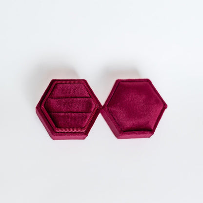 A raspberry hexagon ring box lays open displaying the two ring slots in the base. 