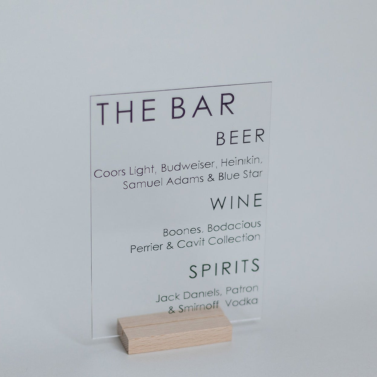 A small acrylic bar menu with black text on a light wood base.