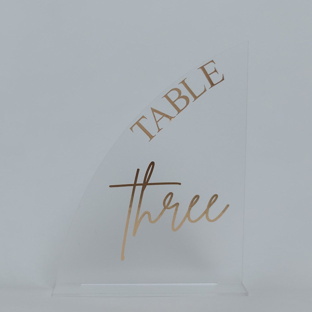 A frosted half arch table number on a frosted acrylic base.