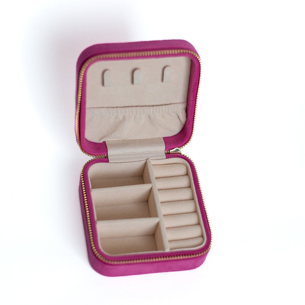 The inside of a fuchsia jewelry case. There are three storage sections and seven ring slots on the bottom portion of the case. On the top half, there are three hooks for chains or necklaces and well as a pouch to tuck them in.