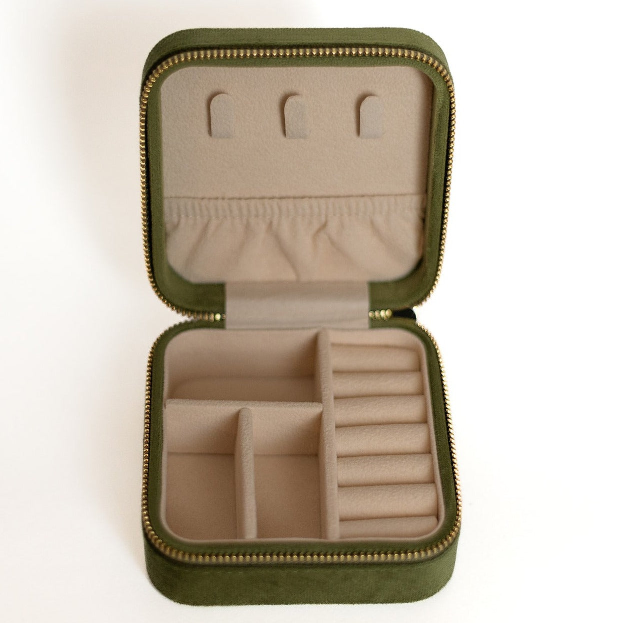 The inside of an olive-coloured jewelry case. There are three storage sections and seven ring slots on the bottom portion of the case. On the top half, there are three hooks for chains or necklaces and well as a pouch to tuck them in.