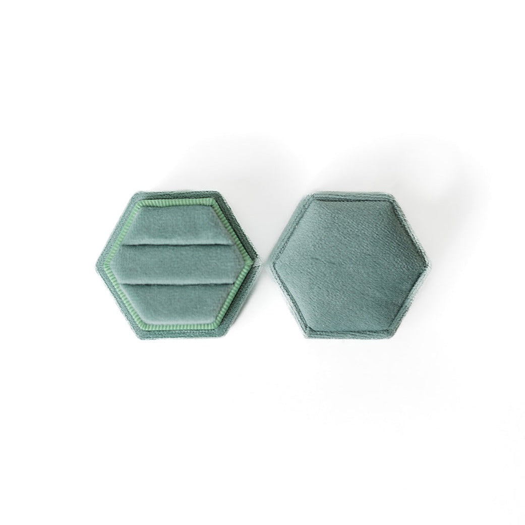 A sage hexagon ring box lays open displaying the two ring slots in the base. 