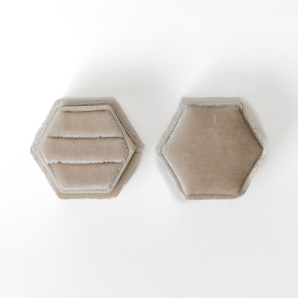 An ivory hexagon ring box lays open displaying the two ring slots in the base. 
