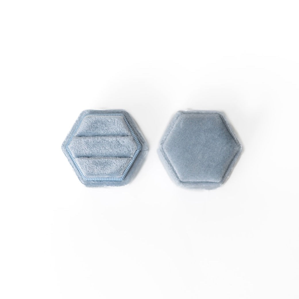 A powder blue hexagon ring box lays open displaying the two ring slots in the base. 