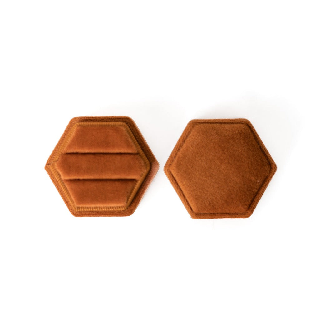 A burnt orange hexagon ring box lays open displaying the two ring slots in the base. 