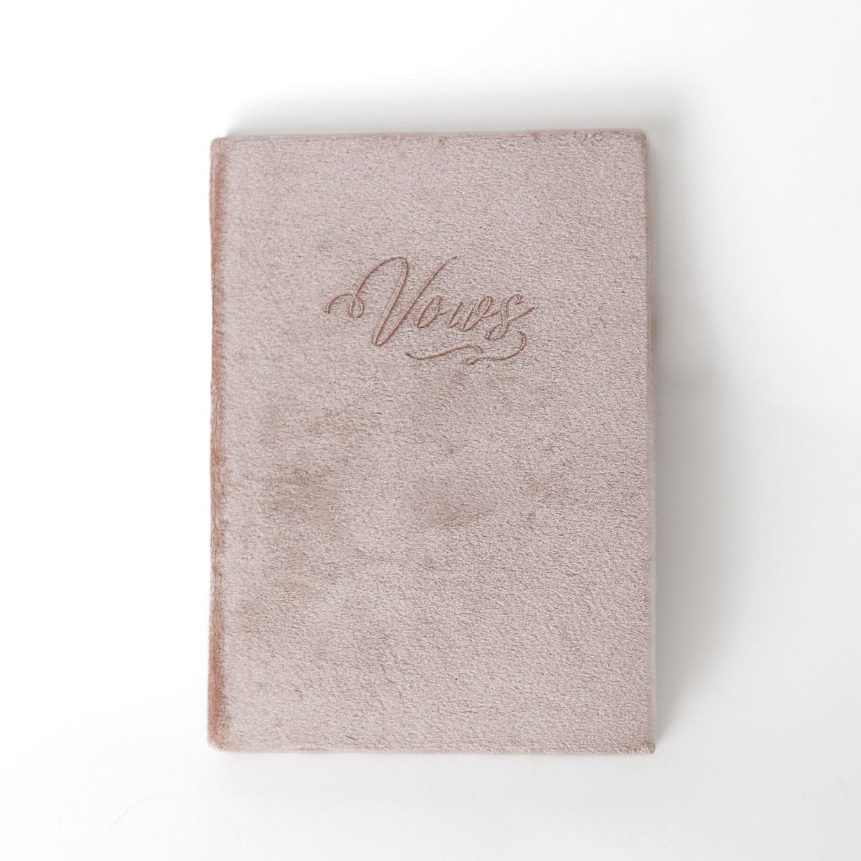 A blush-coloured vow book with the word "Vows" embossed on the front cover.