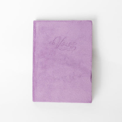 A mauve vow book with the word "Vows" embossed on the front cover.