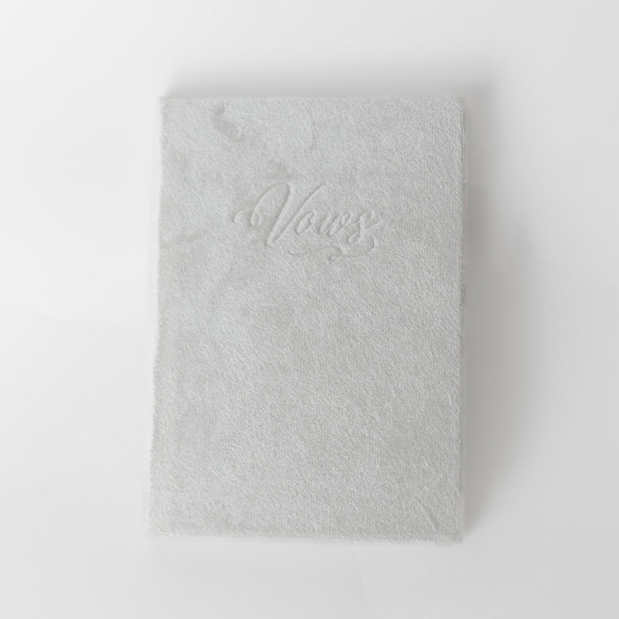 A white vow book with the word "Vows" embossed on the front cover.