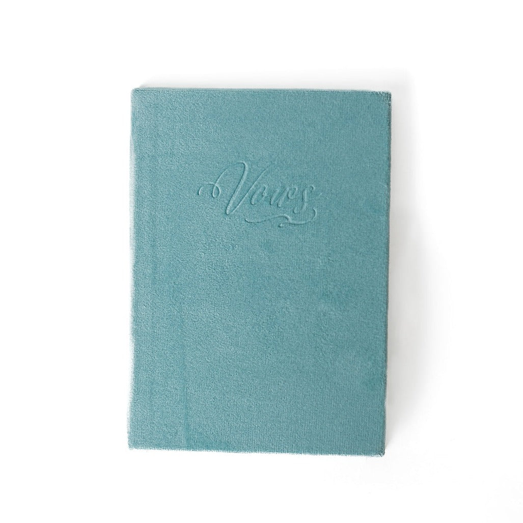 An aqua vow book with the word "Vows" embossed on the front cover.