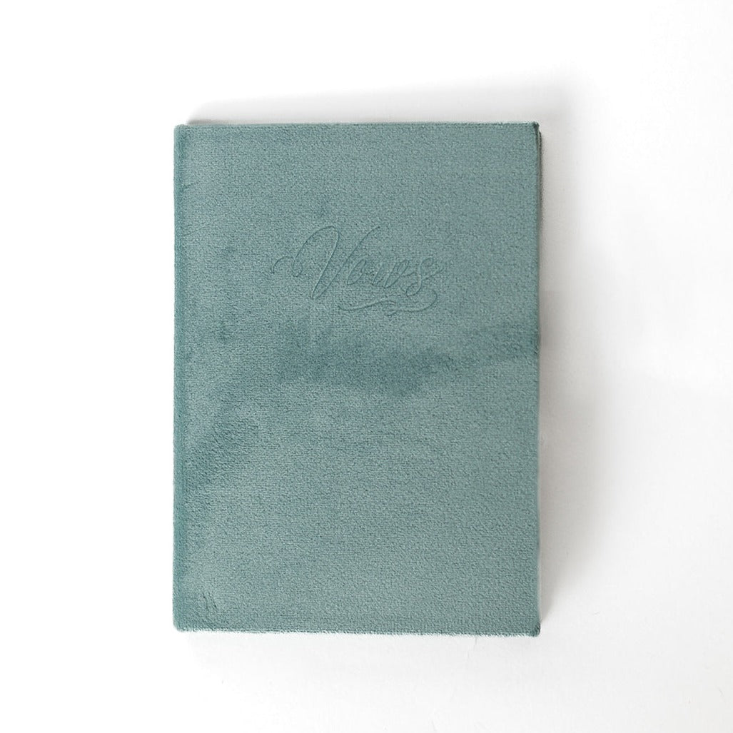 A sage vow book with the word "Vows" embossed on the front cover.