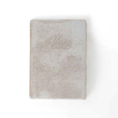 An ivory vow book with the word "Vows" embossed on the front cover.