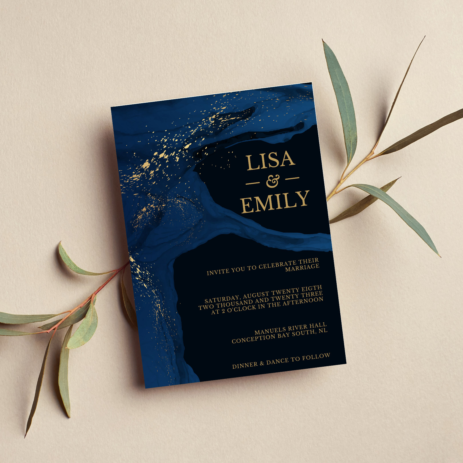 A black, blue and gold wedding invitation sits on top of a cream-coloured background. Underneath the invitation are small branches with thin leaves.