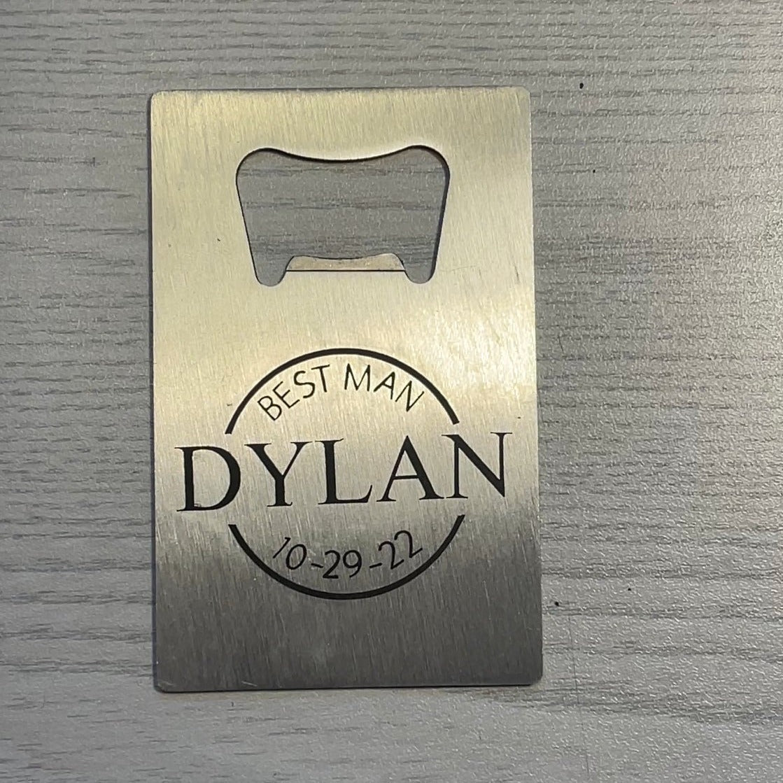 A rectangular credit card sized bottle opener is pictured with a design below the opening, The text in the design frames a circle and reads "Best Man" at the top and "10-29-22" at the bottom. The name "Dylan" cuts through the circle in all capital letters.